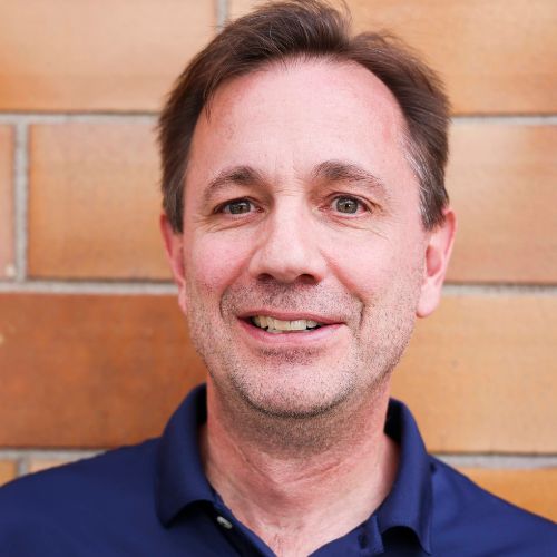 Joe Huisman_website Headshot of Andrea Marie standing in front of a brick building